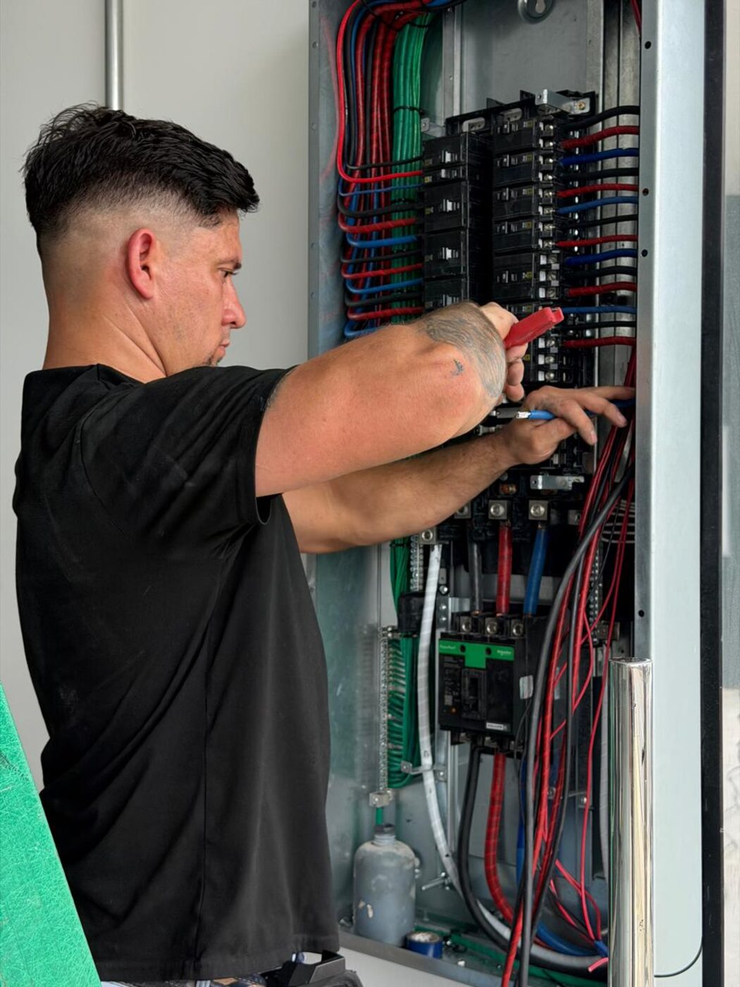 Técnico de Electricem trabajando en un tablero eléctrico trifásico